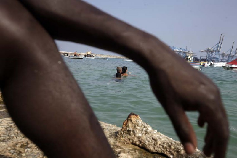 malta-refugiados-brazo-de-negro-con-agua-mar-y-barcos-al-fondo-foto-olmo-calvo.jpg